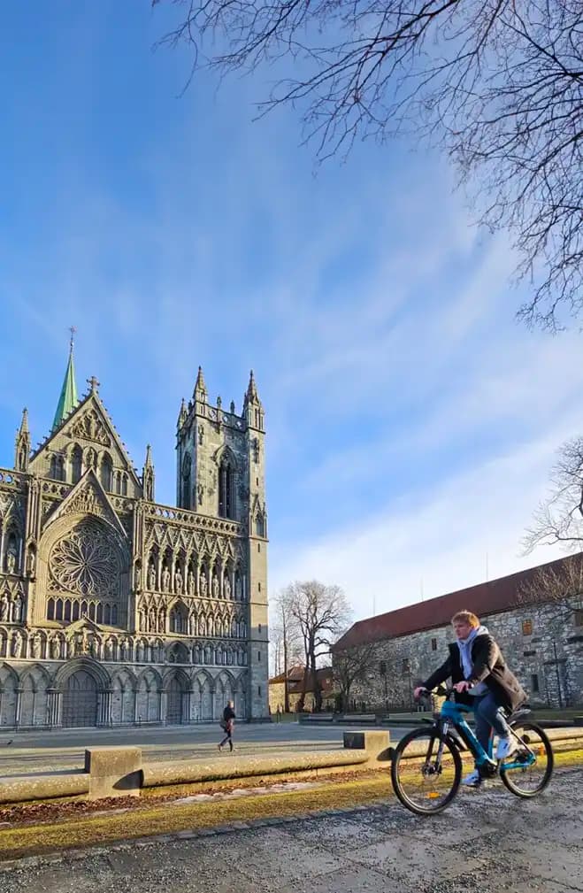 Person på elsykkel med Nidarosdomen i bakgrunn